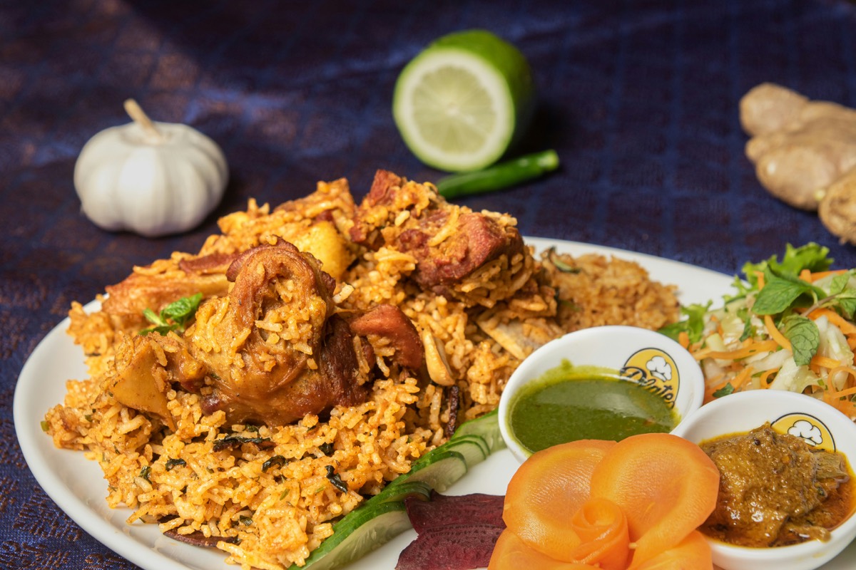 Calcutta biryani with mutton, a whole potato and an egg, served with sides