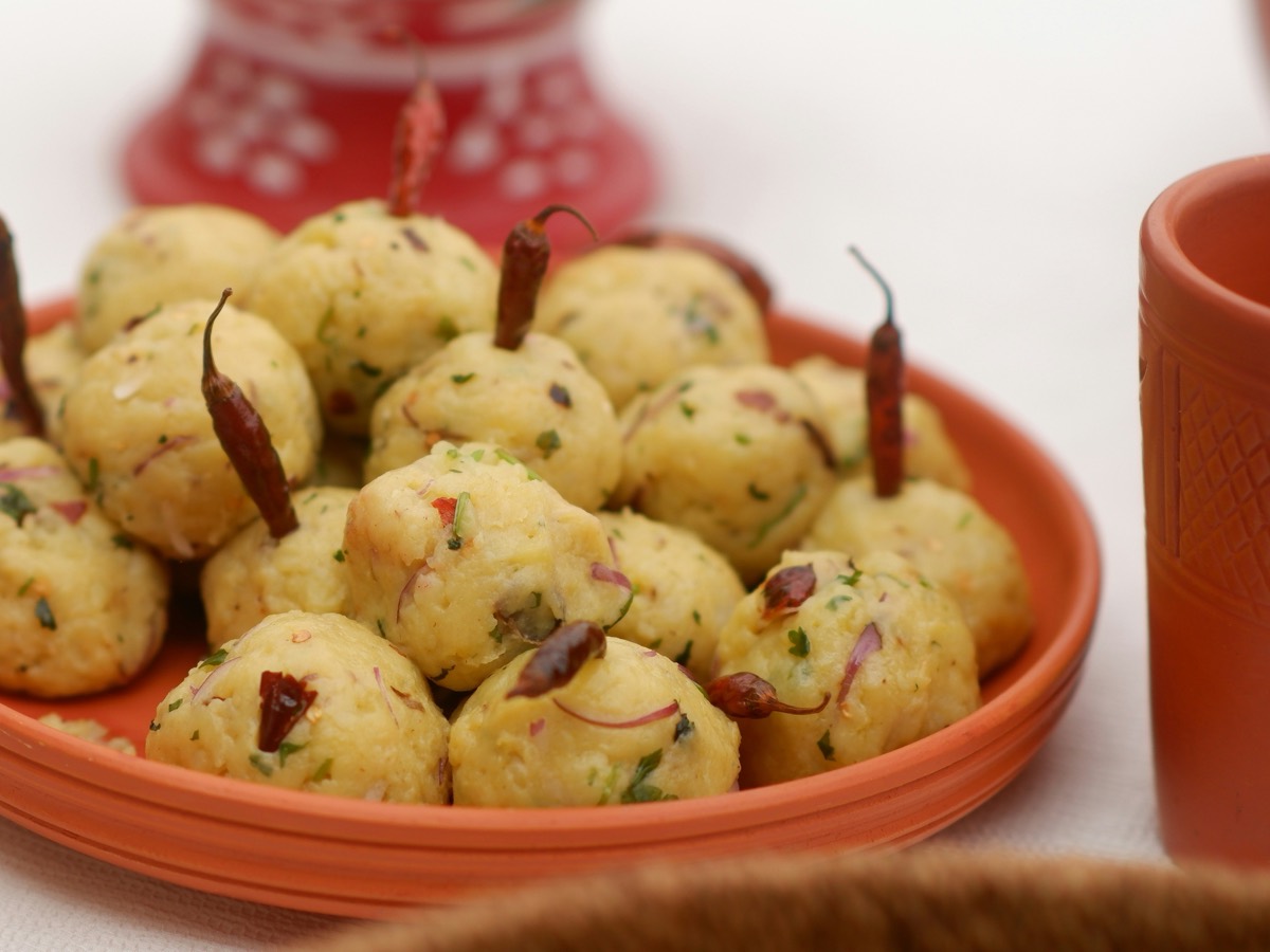 Mashed potato balls with green chillies pressed in, on a terracotta plate