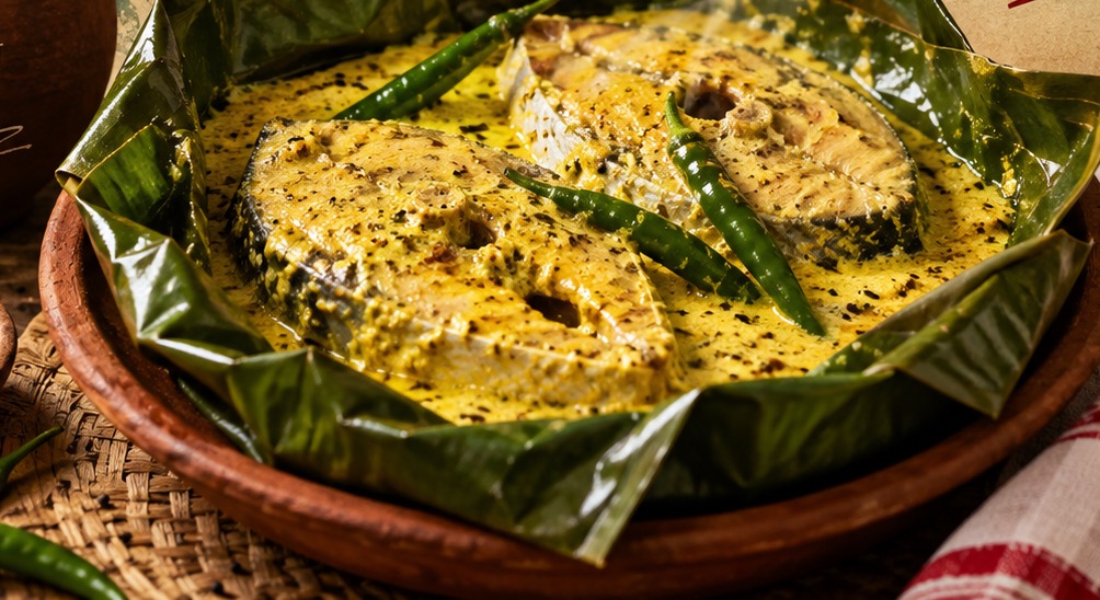 Hilsa steaks under mustard paste, steamed in a banana leaf with whole green chillies