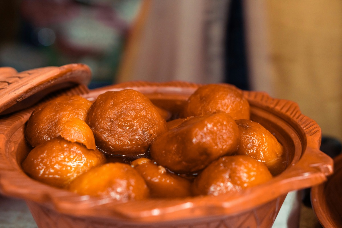 Dark pantua soaking in date palm jaggery syrup in a terracotta bowl